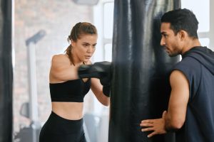 Coach avec une femme réalisant des exercices de cardio boxe sur un punching ball.