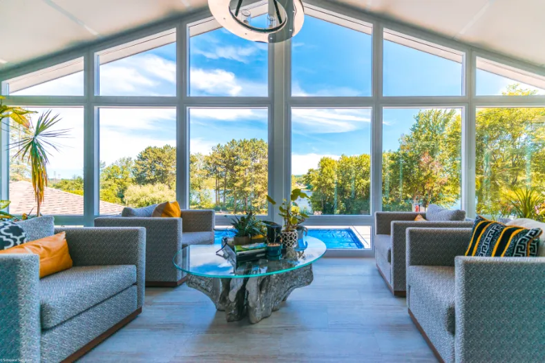 Solarium 4 saisons avec de grandes fenêtres donnant vue sur une terrasse avec piscine